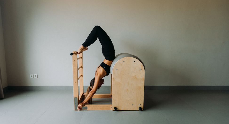 Woman showing the classical Pilates exercise Scorpio on the Ladder Barrel