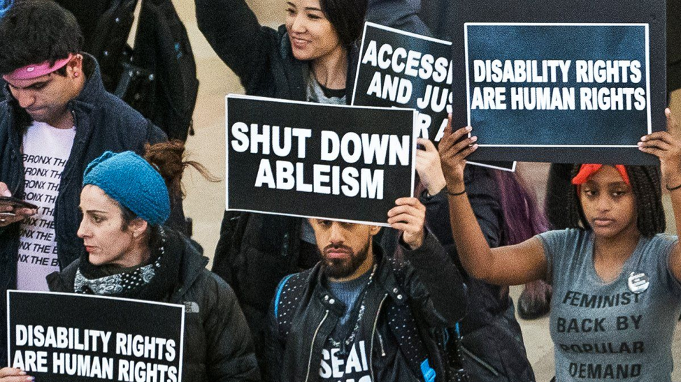 A disability rights march with people holding signs.