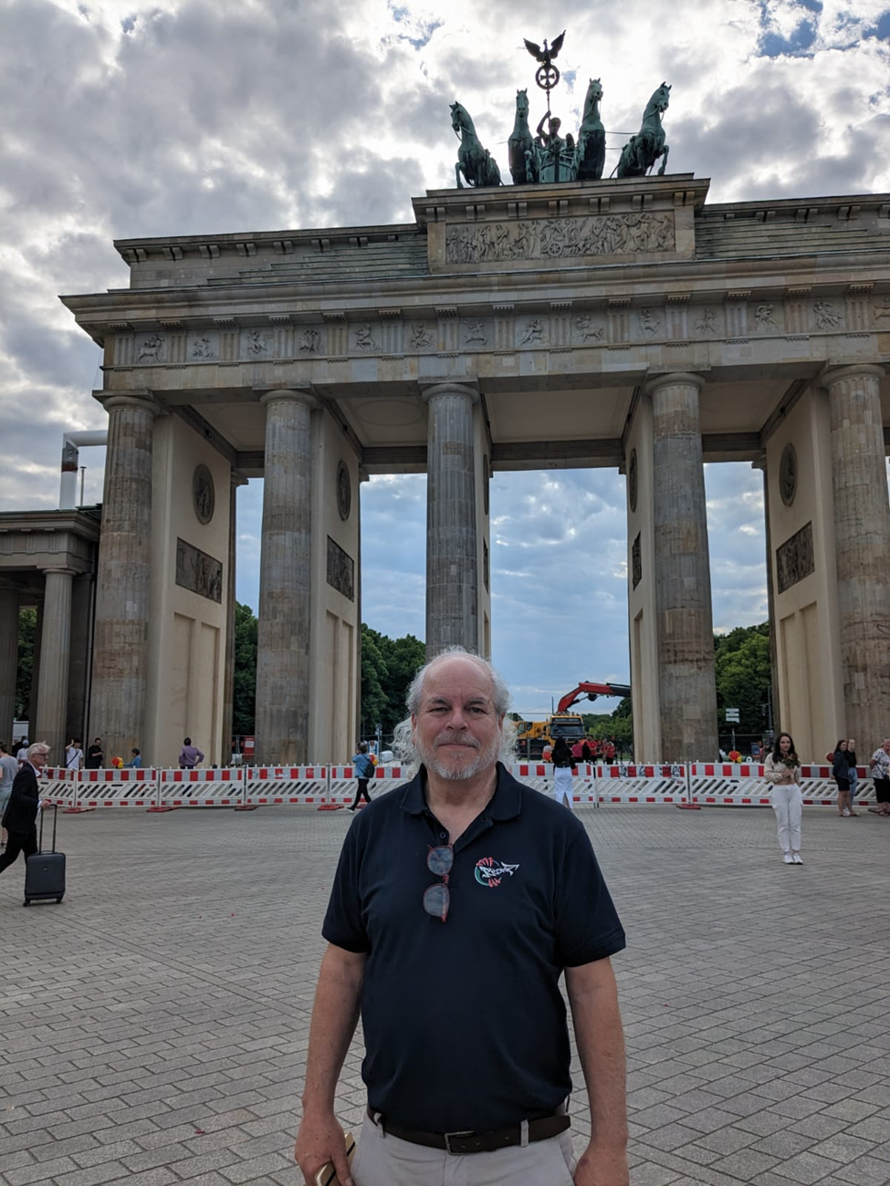 Man standing in front of a large stone pillared gate structure in Berlin Germany