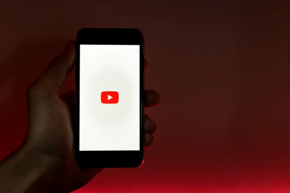 A hand holding a smartphone displaying the YouTube logo