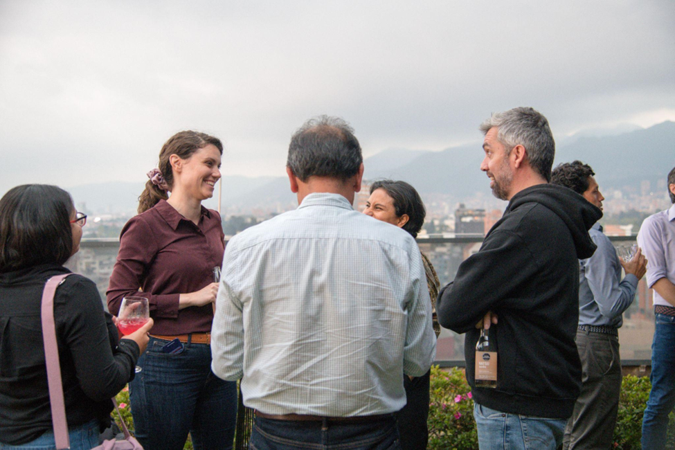 Five workshop participants standing in a circle on a rooftop with mountains in the distance. Participants are laughing and smiling.