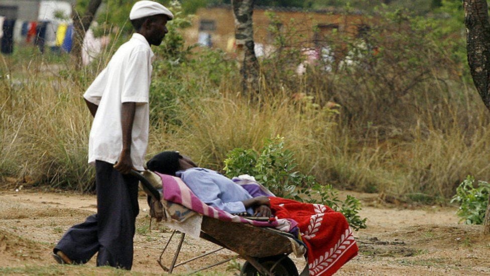 a man transporting his ill wife to a nearby clinic (5km away) in a wheelbarrow