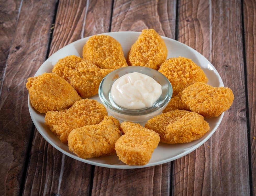 a plate of chicken nugget with a dip in the middle