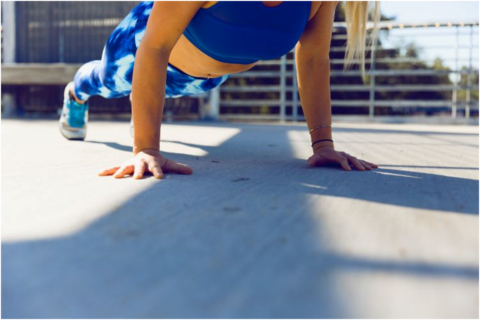 A woman doing pushups on a floor of concrete