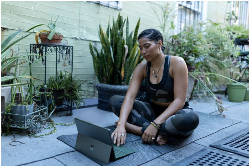 A woman working out while attending yoga classes on her laptop