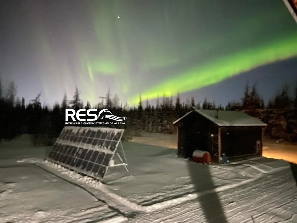 View of solar panels cleared of snow next to the Alaska solar company logo against a background of the northern lights