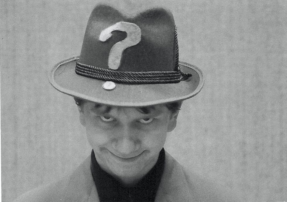 Headshot of a young man in a homemade Riddler costume creepily grinning at the camera.