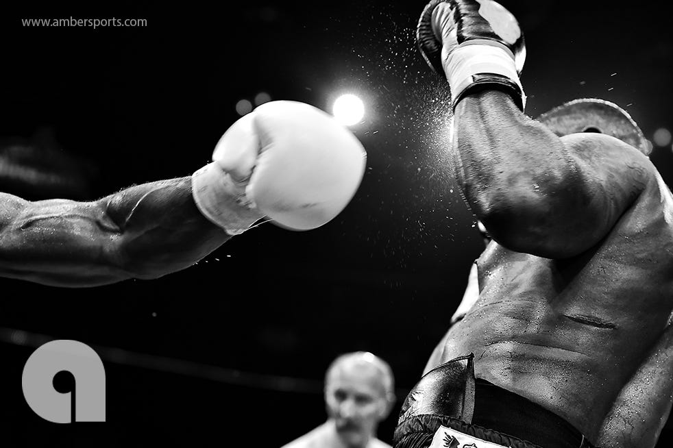 Two determined boxers compete in the ring, delivering powerful punches during an intense boxing match.