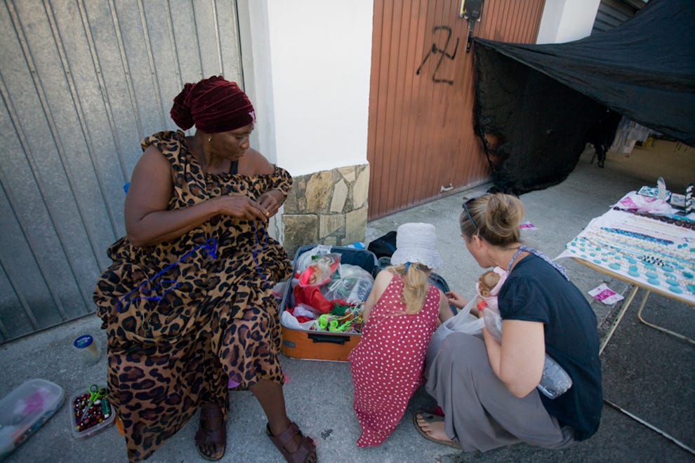 Mama Arima, from Senegal, talks to tourist before braiding the girls hair, in Torrox, Spain