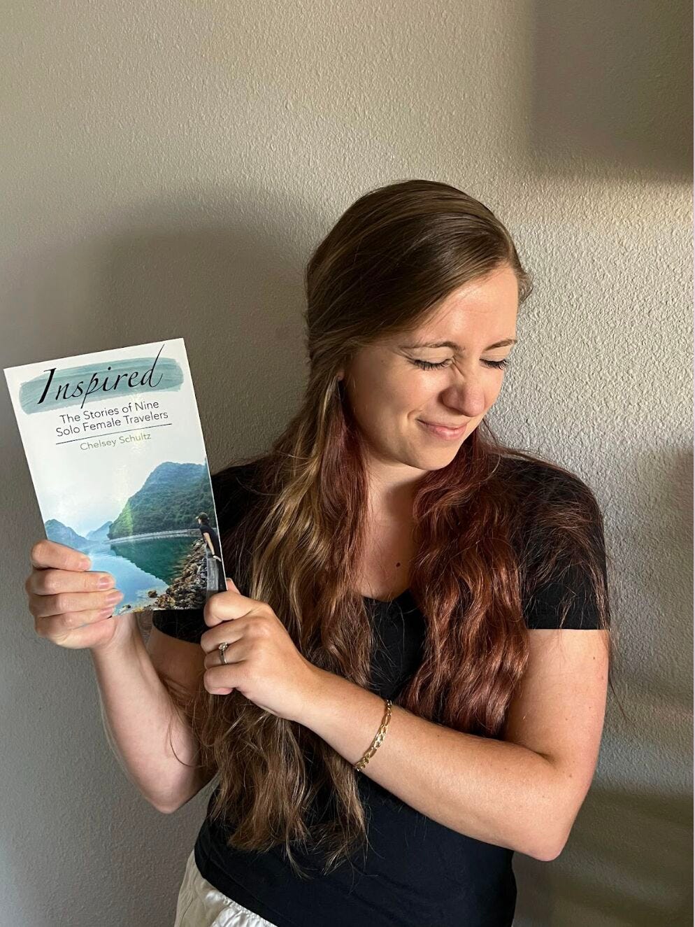 A photo of Chelsey holding the book Inspired: The Stories of Nine Solo Female Travelers.