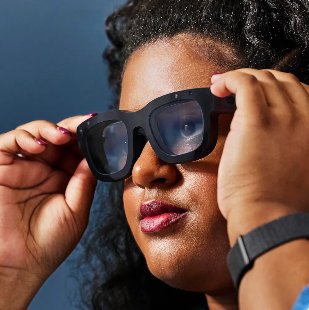 Woman holding and wearing new Meta AI Glasses with tracking strap on her wrist