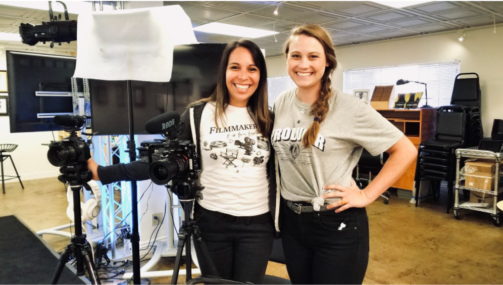 A photo of Natalie and Meredith smiling near two cameras and a light set up.