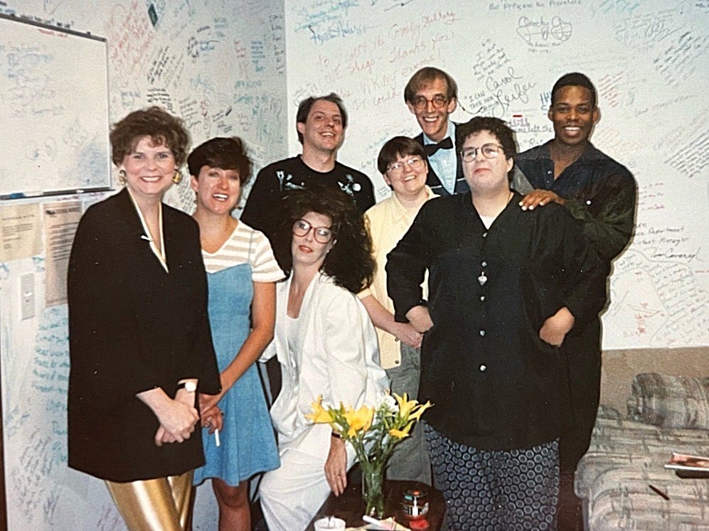Group picture of eight people in room with writing all over the walls.