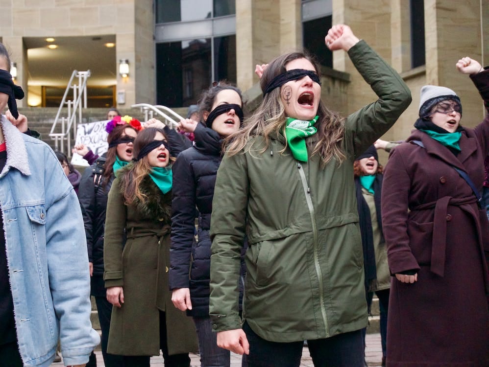A group of white women protesting with a blindfold on