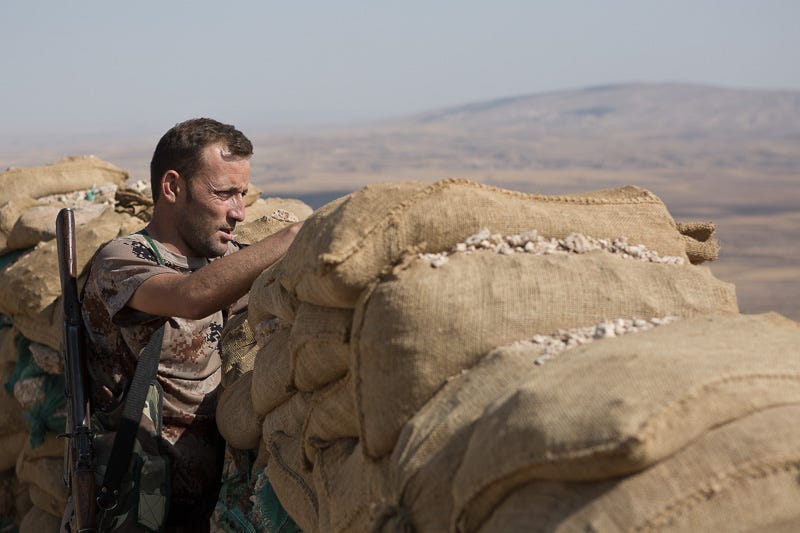 01/09/2015. Bashiqa, Iraq. A Kurdish peshmerga fighter keeps watch from a position on top of Bashiqa Mountain near Mosul, Iraq. Bashiqa Mountain, towering over the town of the same name, is now a heavily fortified front line. Kurdish peshmerga, having withdrawn to the mountain after the August 2014 ISIS offensive, now watch over Islamic State held territory from their sandbagged high-ground positions. Regular exchanges of fire take place between the Kurds and the Islamic militants with the occupied Iraqi city of Mosul forming the backdrop. The town of Bashiqa, a formerly mixed town that had a population of Yazidi, Kurd, Arab and Shabak, now lies empty apart from insurgents. Along with several other urban sprawls the town forms one of the gateways to Iraq's second largest city that will need to be dealt with should the Kurds be called to advance on Mosul.