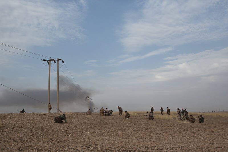 30/09/2015. Kirkuk, Iraq. Peshmerga fighters hunker down as rounds from ISIS snipers and machine gunners fire at Kurds from the village of Mansuriya west of Kirkuk, Iraq. Supported by coalition airstrikes around 3500 peshmerga of the Patriotic Union of Kurdistan (PUK) and the Kurdistan Democratic Party (KDP) engaged in a large offensive to push Islamic State militants out of villages to the west of Kirkuk. During previous offensives ISIS fighters withdrew after sustained coalition air support, but this time in many places militants stayed and fought. The day would see the coalition conduct around 50 airstrikes helping the joint peshmerga force to advance to within a few kilometres of the ISIS stronghold of Hawija and re-take around 17 villages. Around 20 peshmerga lost their lives to improvised explosive devices left by the Islamic State, reports suggest that between 40 and 150 militants were killed.