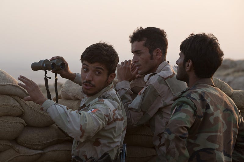 01/09/2015. Bashiqa, Iraq. Iranian Kurdish peshmerga fighters, belonging to 'PAK', a group who work alongside Iraqi Kurdish peshmerga, react to seeing ISIS vehicles moving in the Iraqi town of Bashiqa below their mountain top defensive position. Bashiqa Mountain, towering over the town of the same name, is now a heavily fortified front line. Kurdish peshmerga, having withdrawn to the mountain after the August 2014 ISIS offensive, now watch over Islamic State held territory from their sandbagged high-ground positions. Regular exchanges of fire take place between the Kurds and the Islamic militants with the occupied Iraqi city of Mosul forming the backdrop. The town of Bashiqa, a formerly mixed town that had a population of Yazidi, Kurd, Arab and Shabak, now lies empty apart from insurgents. Along with several other urban sprawls the town forms one of the gateways to Iraq's second largest city that will need to be dealt with should the Kurds be called to advance on Mosul.