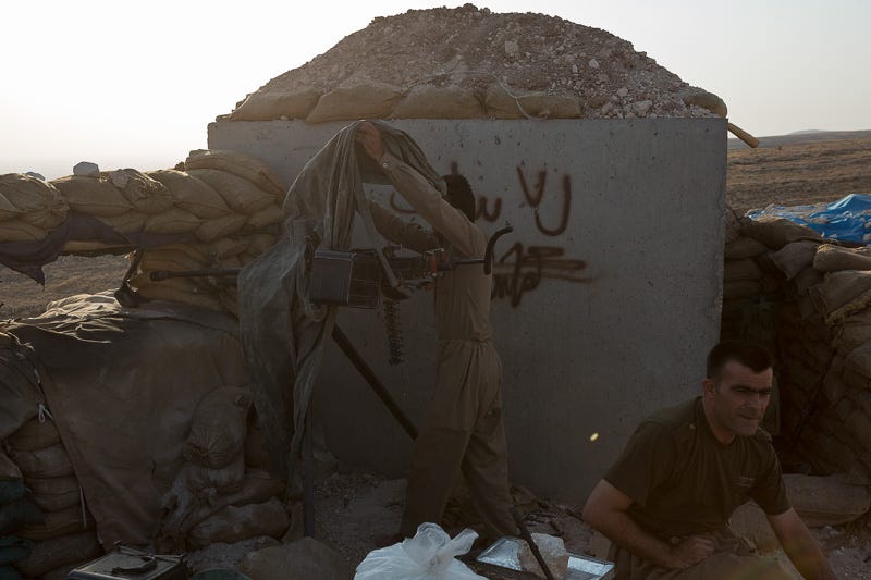 01/09/2015. Bashiqa, Iraq. As the sun goes down a Kurdish peshmerga fighter uncovers a DShK heavy machine gun at a defensive position on top of Bashiqa Mountain near Mosul, Iraq. Bashiqa Mountain, towering over the town of the same name, is now a heavily fortified front line. Kurdish peshmerga, having withdrawn to the mountain after the August 2014 ISIS offensive, now watch over Islamic State held territory from their sandbagged high-ground positions. Regular exchanges of fire take place between the Kurds and the Islamic militants with the occupied Iraqi city of Mosul forming the backdrop. The town of Bashiqa, a formerly mixed town that had a population of Yazidi, Kurd, Arab and Shabak, now lies empty apart from insurgents. Along with several other urban sprawls the town forms one of the gateways to Iraq's second largest city that will need to be dealt with should the Kurds be called to advance on Mosul.