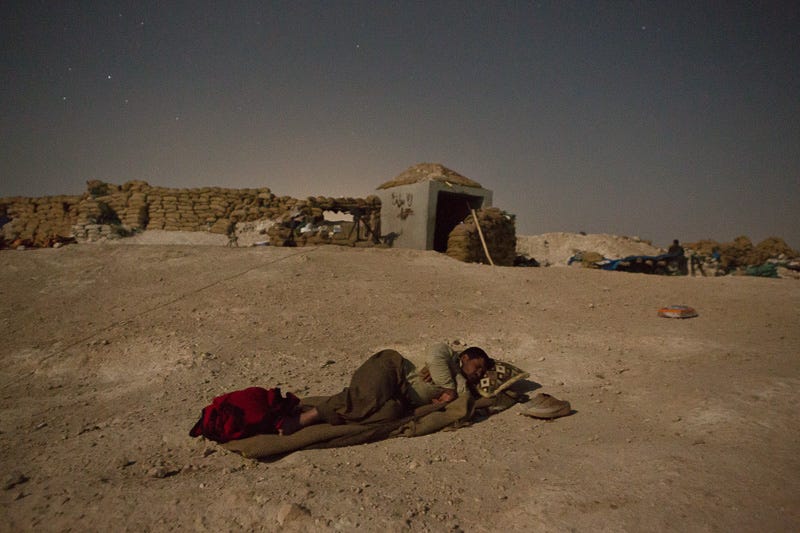 01/09/2015. Bashiqa, Iraq. A Kurdish peshmerga fighter takes advantage of a cool breeze by sleeping under the stars behind his unit's defensive position on Bashiqa Mountain, Iraq. Bashiqa Mountain, towering over the town of the same name, is now a heavily fortified front line. Kurdish peshmerga, having withdrawn to the mountain after the August 2014 ISIS offensive, now watch over Islamic State held territory from their sandbagged high-ground positions. Regular exchanges of fire take place between the Kurds and the Islamic militants with the occupied Iraqi city of Mosul forming the backdrop. The town of Bashiqa, a formerly mixed town that had a population of Yazidi, Kurd, Arab and Shabak, now lies empty apart from insurgents. Along with several other urban sprawls the town forms one of the gateways to Iraq's second largest city that will need to be dealt with should the Kurds be called to advance on Mosul.