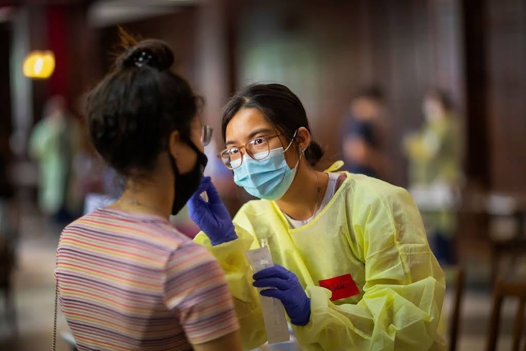 Photo of masked nurse taking patient’s temperature