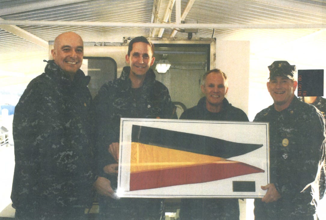 Above - Cmdr. Brian Elkowitz, second from left, and other officers hold the Presidential Unit Citation pennant aboard USS Jimmy Carter. At top - USS Jimmy Carter at sea. Navy photos