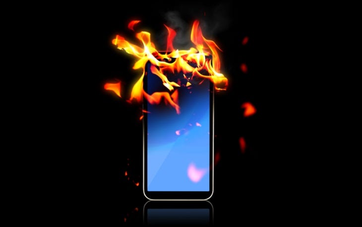 A burning smartphone against a black background