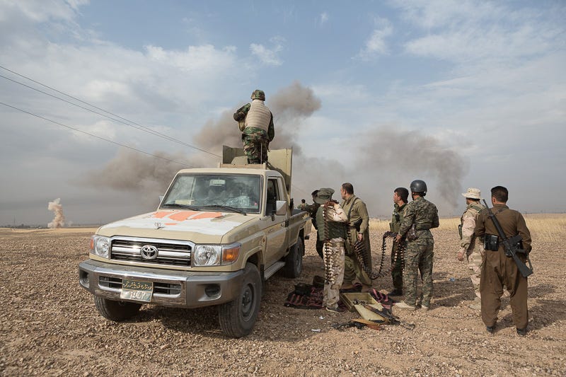 30/09/2015. Kirkuk, Iraq. KDP peshmerga fighters pause from rearming a KPV 14.5mm heavy machine gun to look at the detonation of an ISIS laid improvised explosive device (IED) on the southern edge of the village of Mansuriya, west of Kirkuk, Iraq. The IED was set off by peshmerga entering Mansuriya, the device, and a separate follow up IED, claimed the lives of five fighters. Supported by coalition airstrikes around 3500 peshmerga of the Patriotic Union of Kurdistan (PUK) and the Kurdistan Democratic Party (KDP) engaged in a large offensive to push Islamic State militants out of villages to the west of Kirkuk. During previous offensives ISIS fighters withdrew after sustained coalition air support, but this time in many places militants stayed and fought. The day would see the coalition conduct around 50 airstrikes helping the joint peshmerga force to advance to within a few kilometres of the ISIS stronghold of Hawija and re-take around 17 villages. Around 20 peshmerga lost their lives to improvised explosive devices left by the Islamic State, reports suggest that between 40 and 150 militants were killed.