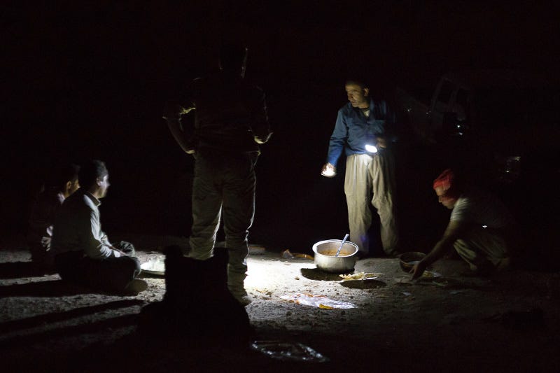 01/09/2015. Bashiqa, Iraq. Kurdish peshmerga make dinner by torchlight at a defensive position on Bashiqa Mountain, Iraq. Bashiqa Mountain, towering over the town of the same name, is now a heavily fortified front line. Kurdish peshmerga, having withdrawn to the mountain after the August 2014 ISIS offensive, now watch over Islamic State held territory from their sandbagged high-ground positions. Regular exchanges of fire take place between the Kurds and the Islamic militants with the occupied Iraqi city of Mosul forming the backdrop. The town of Bashiqa, a formerly mixed town that had a population of Yazidi, Kurd, Arab and Shabak, now lies empty apart from insurgents. Along with several other urban sprawls the town forms one of the gateways to Iraq's second largest city that will need to be dealt with should the Kurds be called to advance on Mosul.