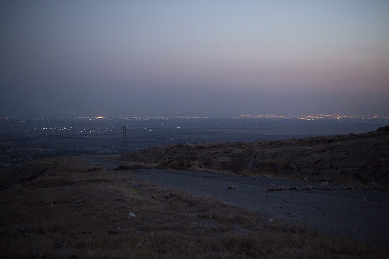 01/09/2015. Bashiqa, Iraq. Lights coming from Islamic State held Mosul, Iraq's second largest city, are seen from Kurdish peshmerga defensive positions on Bashiqa Mountain. Bashiqa Mountain, towering over the town of the same name, is now a heavily fortified front line. Kurdish peshmerga, having withdrawn to the mountain after the August 2014 ISIS offensive, now watch over Islamic State held territory from their sandbagged high-ground positions. Regular exchanges of fire take place between the Kurds and the Islamic militants with the occupied Iraqi city of Mosul forming the backdrop. The town of Bashiqa, a formerly mixed town that had a population of Yazidi, Kurd, Arab and Shabak, now lies empty apart from insurgents. Along with several other urban sprawls the town forms one of the gateways to Iraq's second largest city that will need to be dealt with should the Kurds be called to advance on Mosul.