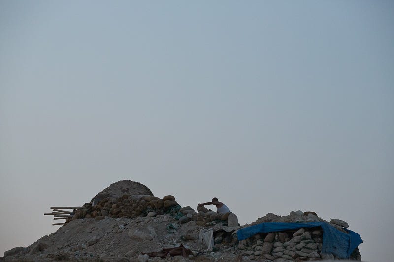 01/09/2015. Bashiqa, Iraq. A Kurdish peshmerga fighter uses sandbags to reinforce a defensive position on the top of Bashiqa Mountain, Iraq. Bashiqa Mountain, towering over the town of the same name, is now a heavily fortified front line. Kurdish peshmerga, having withdrawn to the mountain after the August 2014 ISIS offensive, now watch over Islamic State held territory from their sandbagged high-ground positions. Regular exchanges of fire take place between the Kurds and the Islamic militants with the occupied Iraqi city of Mosul forming the backdrop. The town of Bashiqa, a formerly mixed town that had a population of Yazidi, Kurd, Arab and Shabak, now lies empty apart from insurgents. Along with several other urban sprawls the town forms one of the gateways to Iraq's second largest city that will need to be dealt with should the Kurds be called to advance on Mosul.