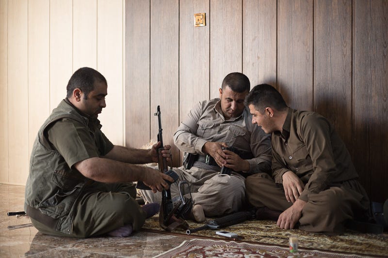 29/09/2015. Chamchamal, Iraq. Hardi (L), Sarwar (C) and Zana, all volunteer peshmerga fighters, reload ammunition ahead of a peshmerga offensive at a comrade's house in Chamchamal, Iraq. Supported by coalition airstrikes around 3500 peshmerga of the Patriotic Union of Kurdistan (PUK) and the Kurdistan Democratic Party (KDP) engaged in a large offensive to push Islamic State militants out of villages to the west of Kirkuk. During previous offensives ISIS fighters withdrew after sustained coalition air support, but this time in many places militants stayed and fought. The day would see the coalition conduct around 50 airstrikes helping the joint peshmerga force to advance to within a few kilometres of the ISIS stronghold of Hawija and re-take around 17 villages. Around 20 peshmerga lost their lives to improvised explosive devices left by the Islamic State, reports suggest that between 40 and 150 militants were killed.