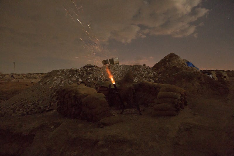 o01/09/2015. Bashiqa, Iraq. A fighter belonging to Iranian Kurdish peshmerga from PAK fires a 60mm mortar from defensive emplacements on the summit of Bashiqa Mountain at ISIS locations within the town of the same name. Bashiqa Mountain, towering over the town of the same name, is now a heavily fortified front line. Kurdish peshmerga, having withdrawn to the mountain after the August 2014 ISIS offensive, now watch over Islamic State held territory from their sandbagged high-ground positions. Regular exchanges of fire take place between the Kurds and the Islamic militants with the occupied Iraqi city of Mosul forming the backdrop. The town of Bashiqa, a formerly mixed town that had a population of Yazidi, Kurd, Arab and Shabak, now lies empty apart from insurgents. Along with several other urban sprawls the town forms one of the gateways to Iraq's second largest city that will need to be dealt with should the Kurds be called to advance on Mosul.