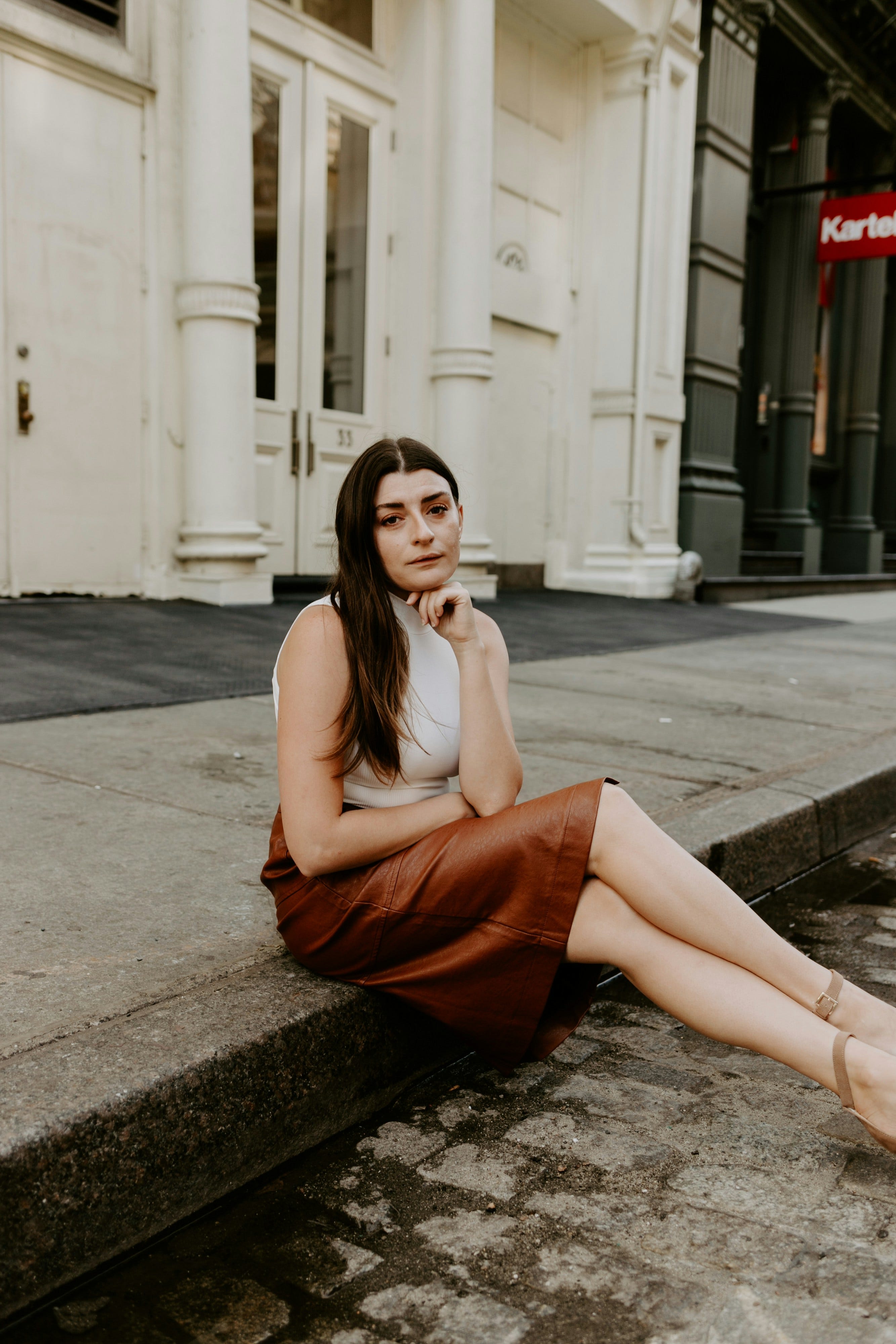 woman in orange sleeveless dress sitting on concrete floor