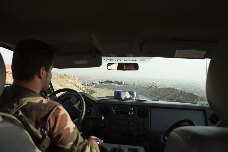 01/09/2015. Bashiqa, Iraq. Islamic State held Iraq is seen beyond Kurdish peshmerga positions through the windscreen of a peshmerga off road vehicle. Bashiqa Mountain, towering over the town of the same name, is now a heavily fortified front line. Kurdish peshmerga, having withdrawn to the mountain after the August 2014 ISIS offensive, now watch over Islamic State held territory from their sandbagged high-ground positions. Regular exchanges of fire take place between the Kurds and the Islamic militants with the occupied Iraqi city of Mosul forming the backdrop. The town of Bashiqa, a formerly mixed town that had a population of Yazidi, Kurd, Arab and Shabak, now lies empty apart from insurgents. Along with several other urban sprawls the town forms one of the gateways to Iraq's second largest city that will need to be dealt with should the Kurds be called to advance on Mosul.