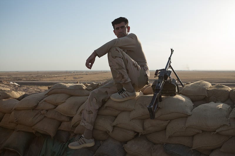 29/09/2015. Kirkuk, Iraq. A peshmerga sits on a sandbag wall next to a PKM machine gun at a front line west of Kirkuk, Iraq. Supported by coalition airstrikes around 3500 peshmerga of the Patriotic Union of Kurdistan (PUK) and the Kurdistan Democratic Party (KDP) engaged in a large offensive to push Islamic State militants out of villages to the west of Kirkuk. During previous offensives ISIS fighters withdrew after sustained coalition air support, but this time in many places militants stayed and fought. The day would see the coalition conduct around 50 airstrikes helping the joint peshmerga force to advance to within a few kilometres of the ISIS stronghold of Hawija and re-take around 17 villages. Around 20 peshmerga lost their lives to improvised explosive devices left by the Islamic State, reports suggest that between 40 and 150 militants were killed.