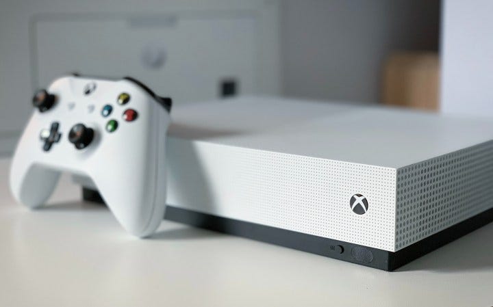 The Xbox Series S is placed on a white table with the controller directly in front of it