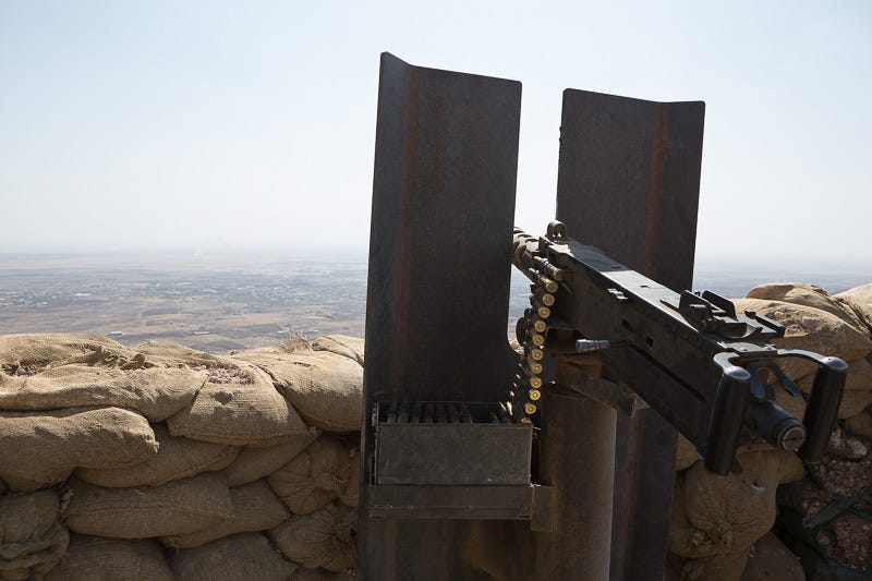 01/09/2015. Bashiqa, Iraq. An American made .50 caliber Browning heavy machine gun, donated by coalition forces, is seen at a peshmerga position on Bashiqa mountain near Mosul, Iraq. Bashiqa Mountain, towering over the town of the same name, is now a heavily fortified front line. Kurdish peshmerga, having withdrawn to the mountain after the August 2014 ISIS offensive, now watch over Islamic State held territory from their sandbagged high-ground positions. Regular exchanges of fire take place between the Kurds and the Islamic militants with the occupied Iraqi city of Mosul forming the backdrop. The town of Bashiqa, a formerly mixed town that had a population of Yazidi, Kurd, Arab and Shabak, now lies empty apart from insurgents. Along with several other urban sprawls the town forms one of the gateways to Iraq's second largest city that will need to be dealt with should the Kurds be called to advance on Mosul.