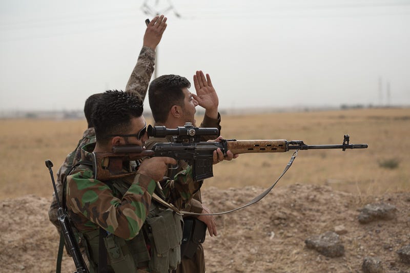 30/09/2015. Kirkuk, Iraq. Kurdish peshmerga and volunteer peshmerga wave and call to get the attention of comrades to bring up a stretcher and evacuate colleagues injured in an explosion caused by an Islamic State improvised explosive device. Supported by coalition airstrikes around 3500 peshmerga of the Patriotic Union of Kurdistan (PUK) and the Kurdistan Democratic Party (KDP) engaged in a large offensive to push Islamic State militants out of villages to the west of Kirkuk. During previous offensives ISIS fighters withdrew after sustained coalition air support, but this time in many places militants stayed and fought. The day would see the coalition conduct around 50 airstrikes helping the joint peshmerga force to advance to within a few kilometres of the ISIS stronghold of Hawija and re-take around 17 villages. Around 20 peshmerga lost their lives to improvised explosive devices left by the Islamic State, reports suggest that between 40 and 150 militants were killed.