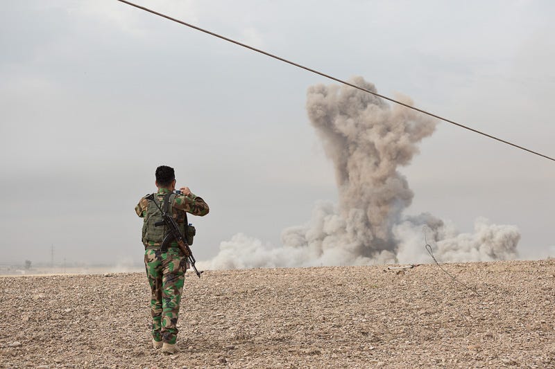 30/09/2015. Kirkuk, Iraq. A KDP peshmerga fighter takes a camera phone picture of a large plume of dust and smoke, one of two large bombs dropped on the village of Mansuriya by coalition aircraft to neutralise Islamic State positions that were pinning down peshmerga fighters during a Kurdish advance west of Kirkuk, Iraq. Supported by coalition airstrikes around 3500 peshmerga of the Patriotic Union of Kurdistan (PUK) and the Kurdistan Democratic Party (KDP) engaged in a large offensive to push Islamic State militants out of villages to the west of Kirkuk. During previous offensives ISIS fighters withdrew after sustained coalition air support, but this time in many places militants stayed and fought. The day would see the coalition conduct around 50 airstrikes helping the joint peshmerga force to advance to within a few kilometres of the ISIS stronghold of Hawija and re-take around 17 villages. Around 20 peshmerga lost their lives to improvised explosive devices left by the Islamic State, reports suggest that between 40 and 150 militants were killed.