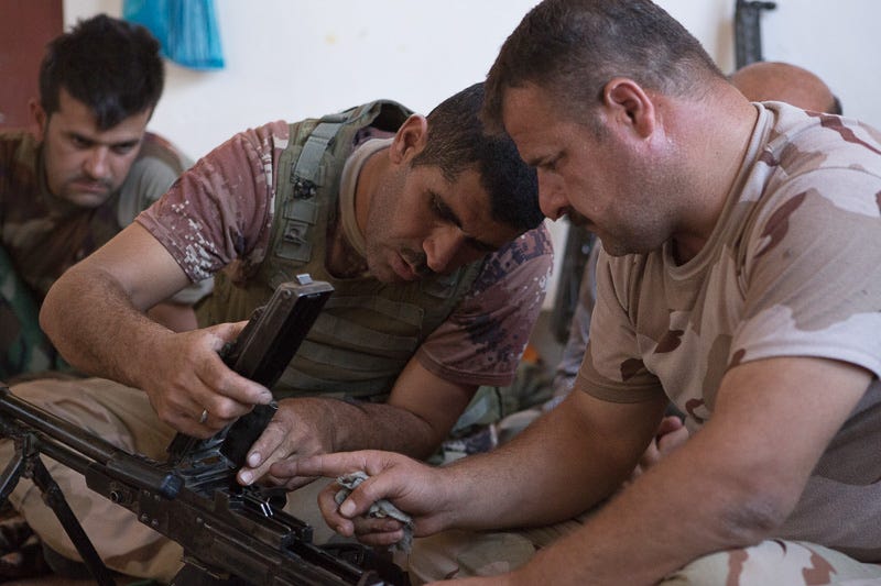 01/09/2015. Bashiqa, Iraq. Two Kurdish peshmerga fighters clean an M84 general purpose machine gun during downtime at a peshmerga position on Bashiqa Mountain near Mosul. Bashiqa Mountain, towering over the town of the same name, is now a heavily fortified front line. Kurdish peshmerga, having withdrawn to the mountain after the August 2014 ISIS offensive, now watch over Islamic State held territory from their sandbagged high-ground positions. Regular exchanges of fire take place between the Kurds and the Islamic militants with the occupied Iraqi city of Mosul forming the backdrop. The town of Bashiqa, a formerly mixed town that had a population of Yazidi, Kurd, Arab and Shabak, now lies empty apart from insurgents. Along with several other urban sprawls the town forms one of the gateways to Iraq's second largest city that will need to be dealt with should the Kurds be called to advance on Mosul.