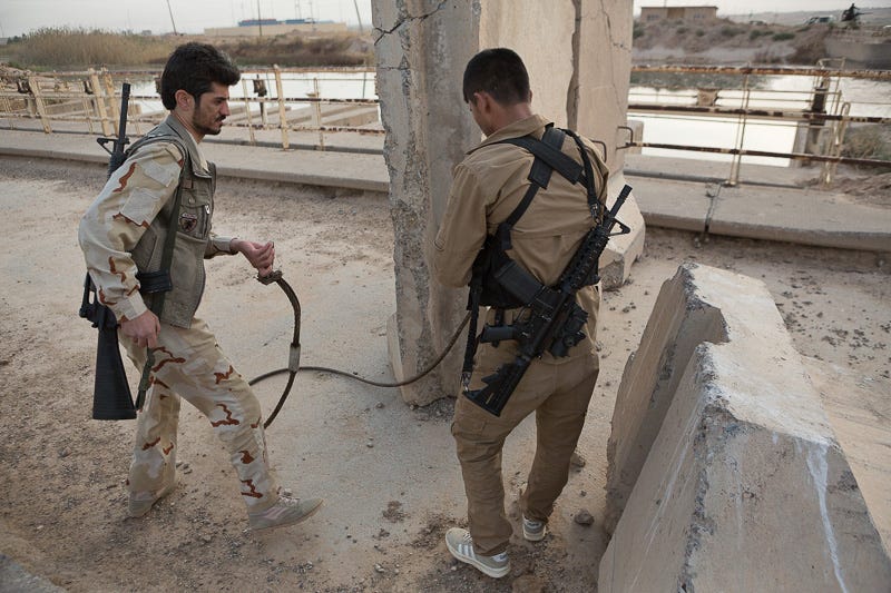 30/09/2015. Kirkuk, Iraq. Kurdish peshmerga fighters attach a steel strop to a concrete barrier, erected by ISIS militants to deny passage across a bridge, near the Iraqi town of Mansuriya during a large offensive by Kurdish security forces west of Kirkuk, Iraq. Supported by coalition airstrikes around 3500 peshmerga of the Patriotic Union of Kurdistan (PUK) and the Kurdistan Democratic Party (KDP) engaged in a large offensive to push Islamic State militants out of villages to the west of Kirkuk. During previous offensives ISIS fighters withdrew after sustained coalition air support, but this time in many places militants stayed and fought. The day would see the coalition conduct around 50 airstrikes helping the joint peshmerga force to advance to within a few kilometres of the ISIS stronghold of Hawija and re-take around 17 villages. Around 20 peshmerga lost their lives to improvised explosive devices left by the Islamic State, reports suggest that between 40 and 150 militants were killed.