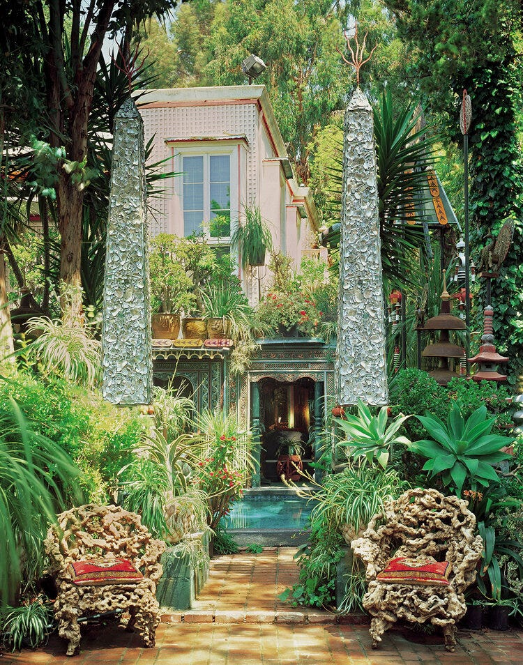 Crushed abalone shell obelisks, many exotic plants, pink house and chairs.