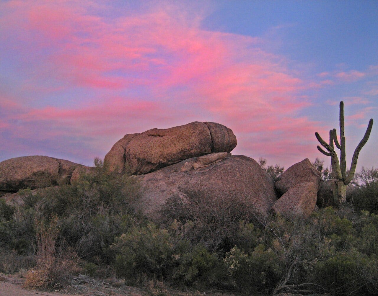 A rock formation bearing a resemblance to a penis against a pink sunset