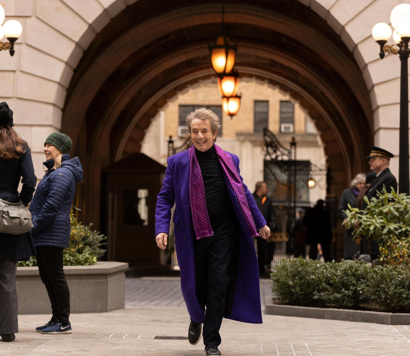 Martin Short framed in an archway wearing a purple coat and purple scarf.