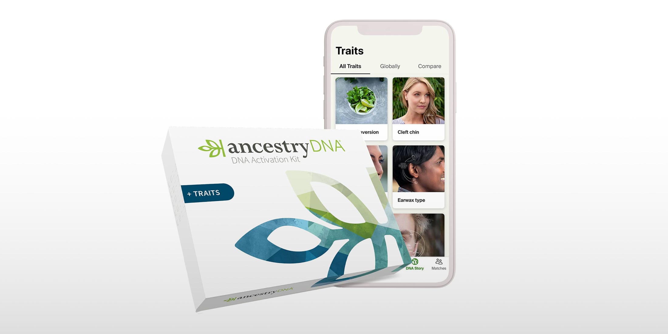 A phone in the background with the Ancestry app open showing two rows of photos depicting a list of traits to choose from including a cleft chin and earwax type. In the foreground the Ancestry DNA Activation Kit is angled slightly and covering the lower left hand part of the phone.