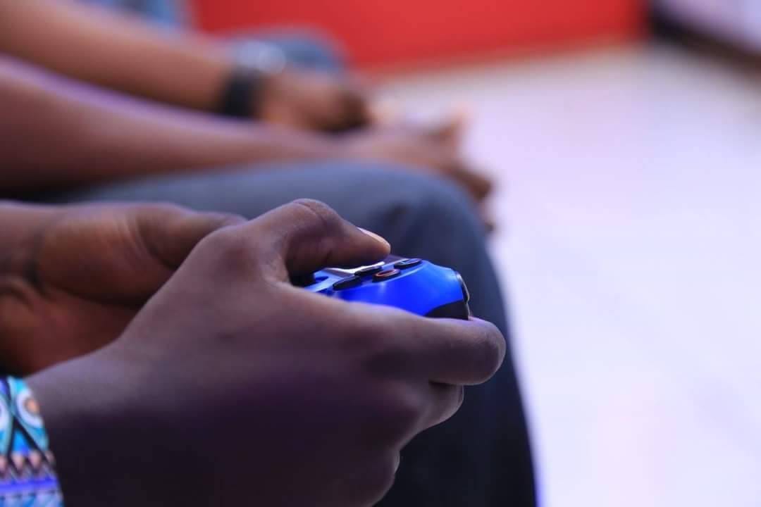Photo of a man's handing holding a blue PlayStation controller during a gaming event, typical of nerd spaces